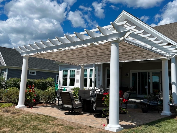 A fiberglass pergola with an overhead shade and a roll up shade